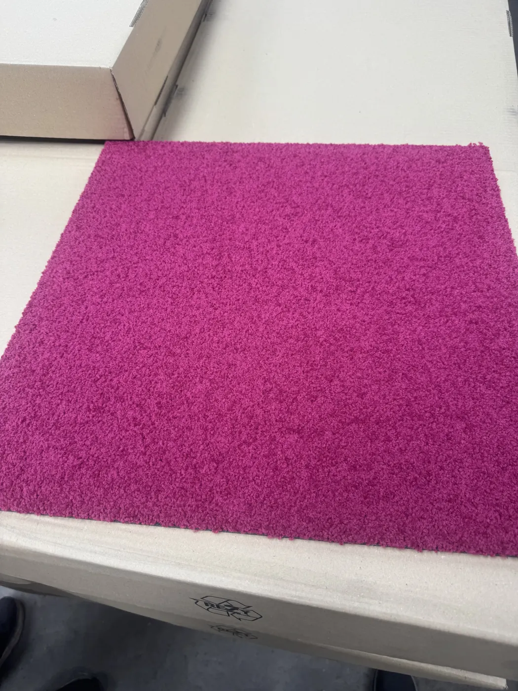 Row of assorted carpet tile colour samples on gravel