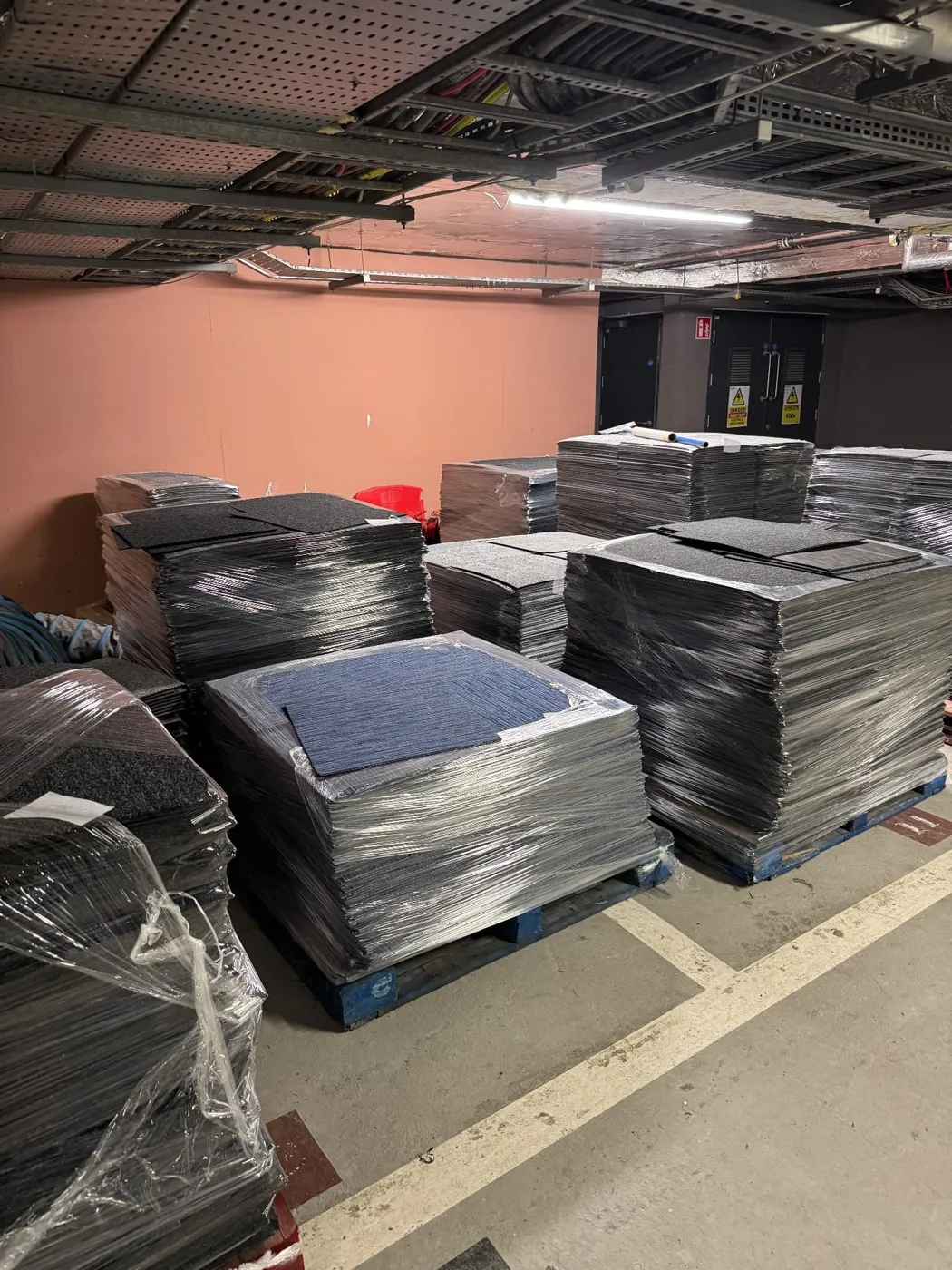 Pallets of reclaimed commercial carpet tiles, shrink-wrapped and ready for collection